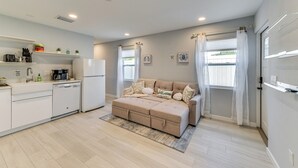 Une cuisine moderne avec des appareils électroménagers blancs, un canapé beige et un tapis.