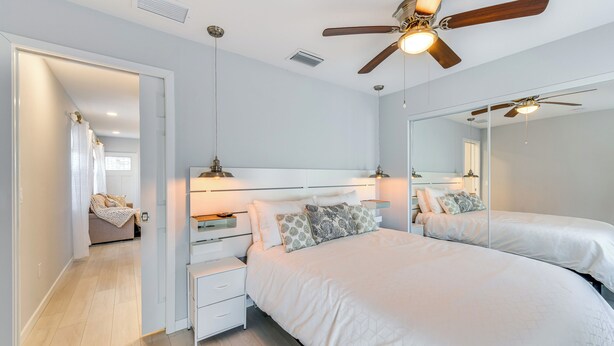 Une chambre avec un grand lit, un ventilateur de plafond et un miroir.