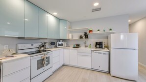Une cuisine moderne avec des meubles blancs, un four encastré, un four à micro-ondes et un réfrigérateur.
