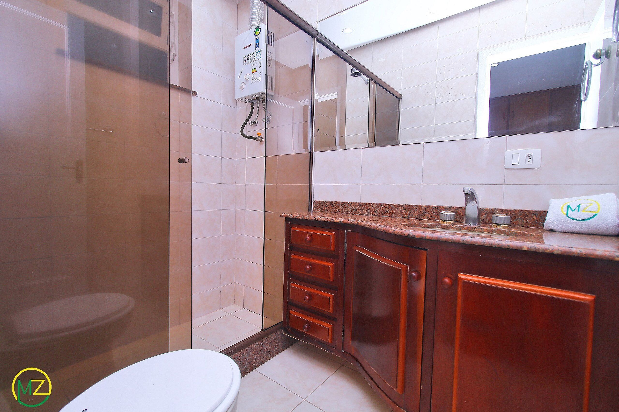 A bathroom with a toilet, a shower, and a sink with a mirror above it.