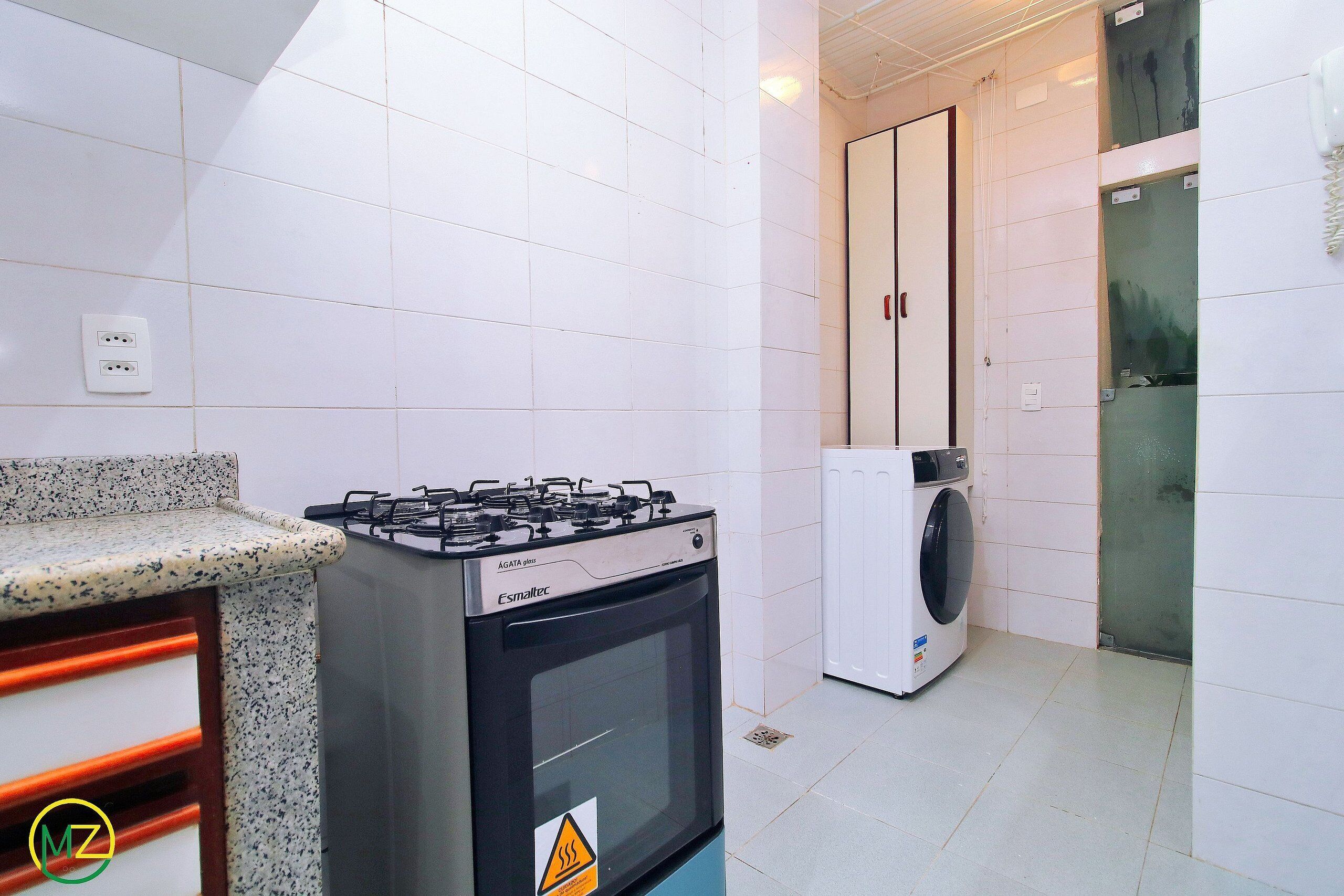 A kitchen with a gas stove, a washing machine, and a cabinet.