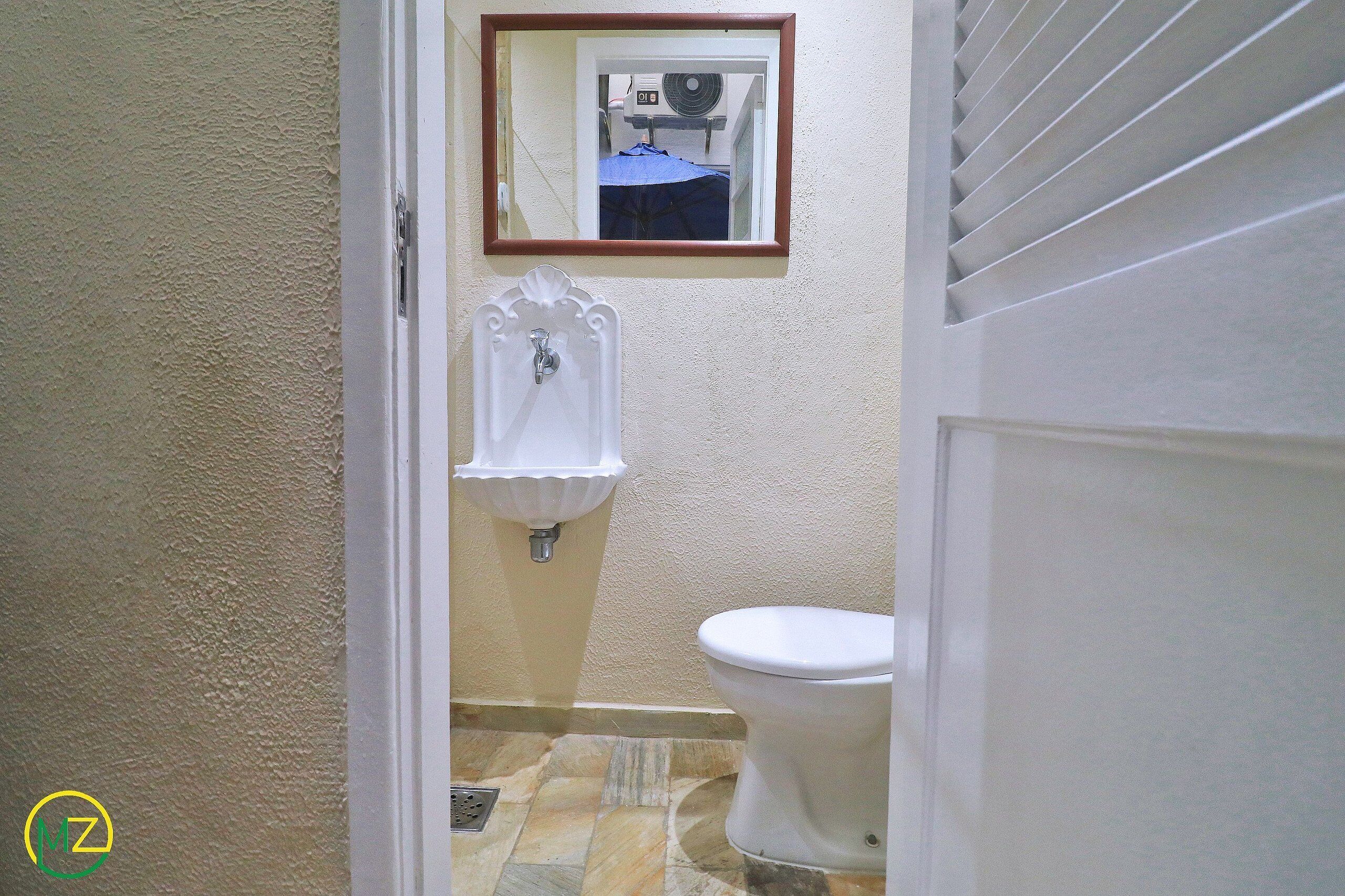Un baño con inodoro, lavamanos y espejo.