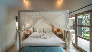 A four-poster bed with a canopy, a bedside table with a lamp, and a view of the outdoors through a large window.