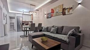 A modern living room with a grey sofa, a wooden coffee table, and a dining area with chairs and a table.