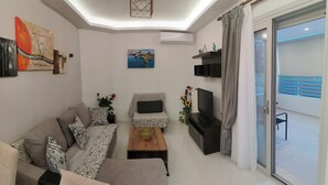 A modern living room with a sofa, armchair, coffee table, TV, and artwork on the walls.