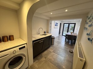 A laundry area with a washing machine, a sink, and a trash bin. - 3 Double Bed Character Cottage in Quiet Hamlet (Tregoodwell)