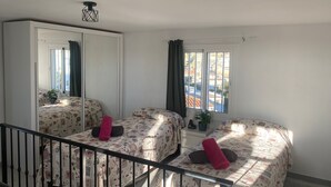 A bedroom with two beds, a large mirror, a window with curtains, and a staircase. - 1029 Casa Evelyn C (Nerja)
