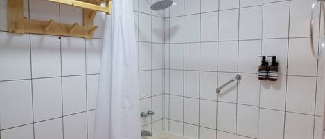 Un baño con bañera, ducha, inodoro y toallero.