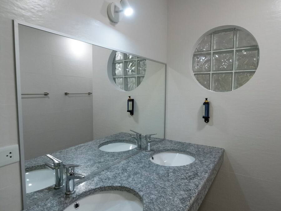 Un baño con dos lavamanos, un espejo grande y un ventanal redondo.