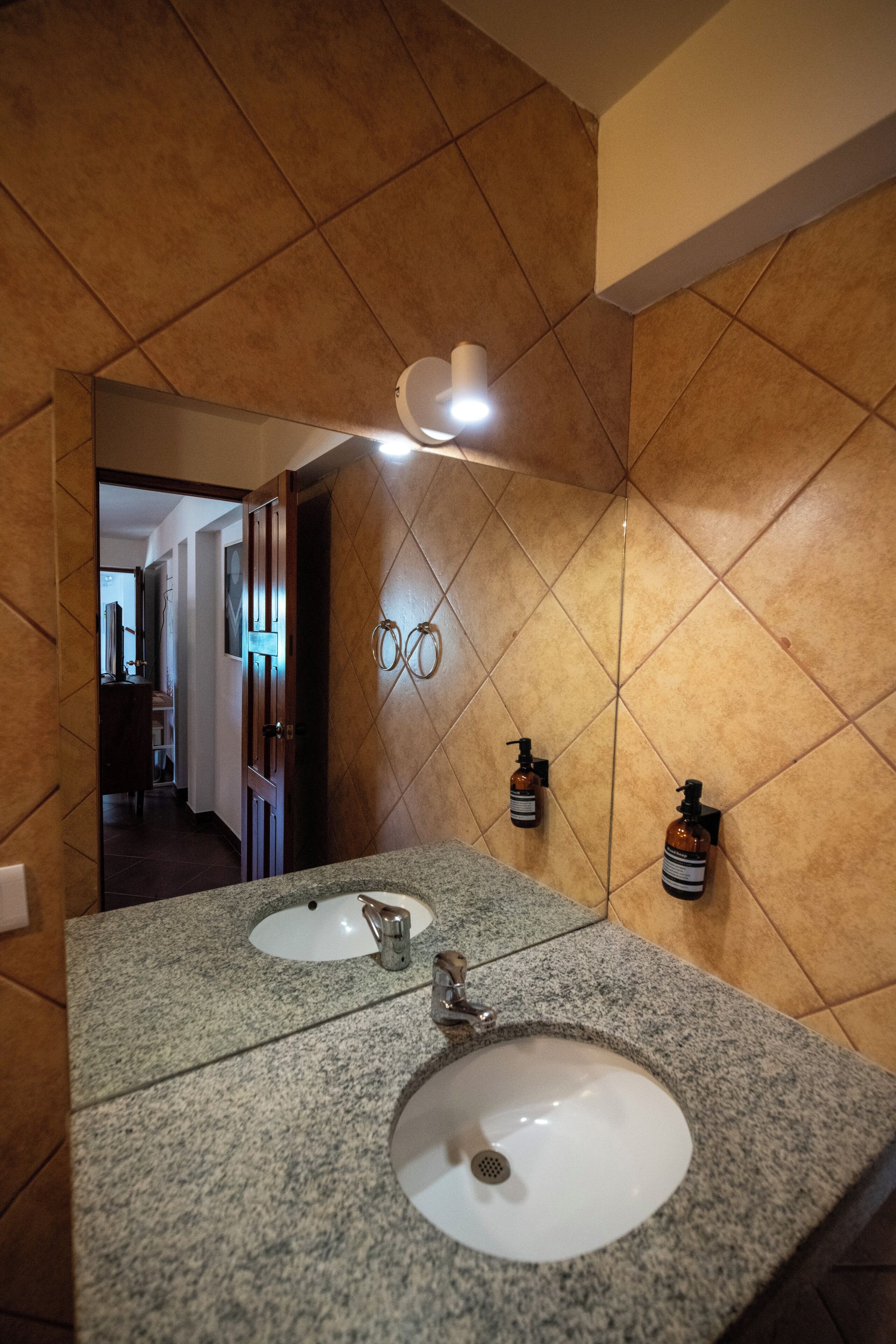 A bathroom with two sinks, a mirror, and a light fixture.