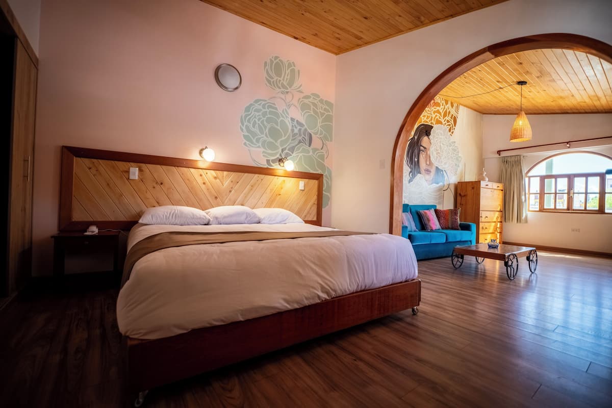 Un dormitorio espacioso con una cama grande, cabecero de madera y un original mural floral.