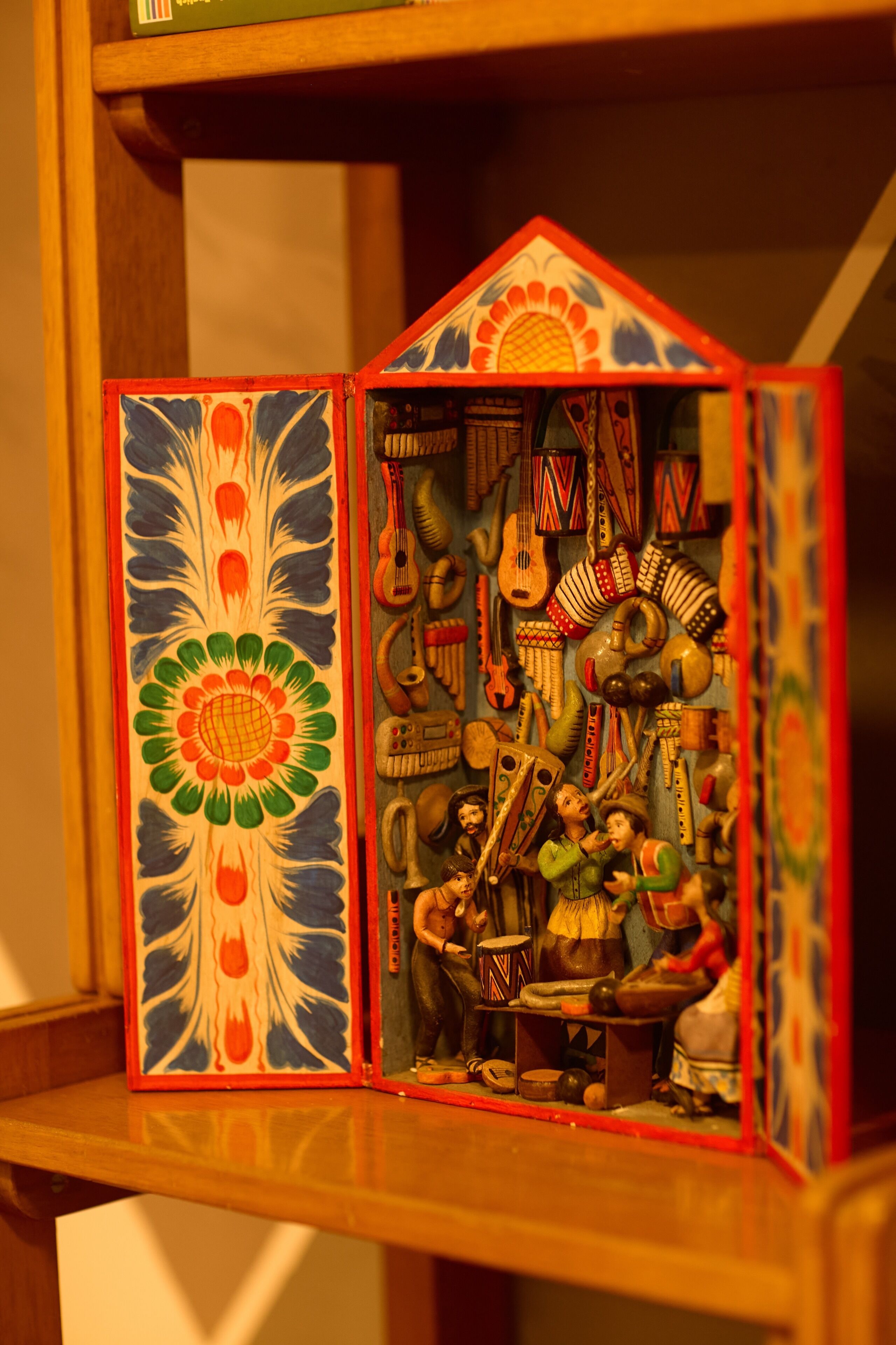 A model of a house with a colorful exterior and a detailed interior featuring various musical instruments and figurines.