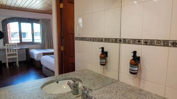 A bathroom with two sinks, a mirror, and a shower area.