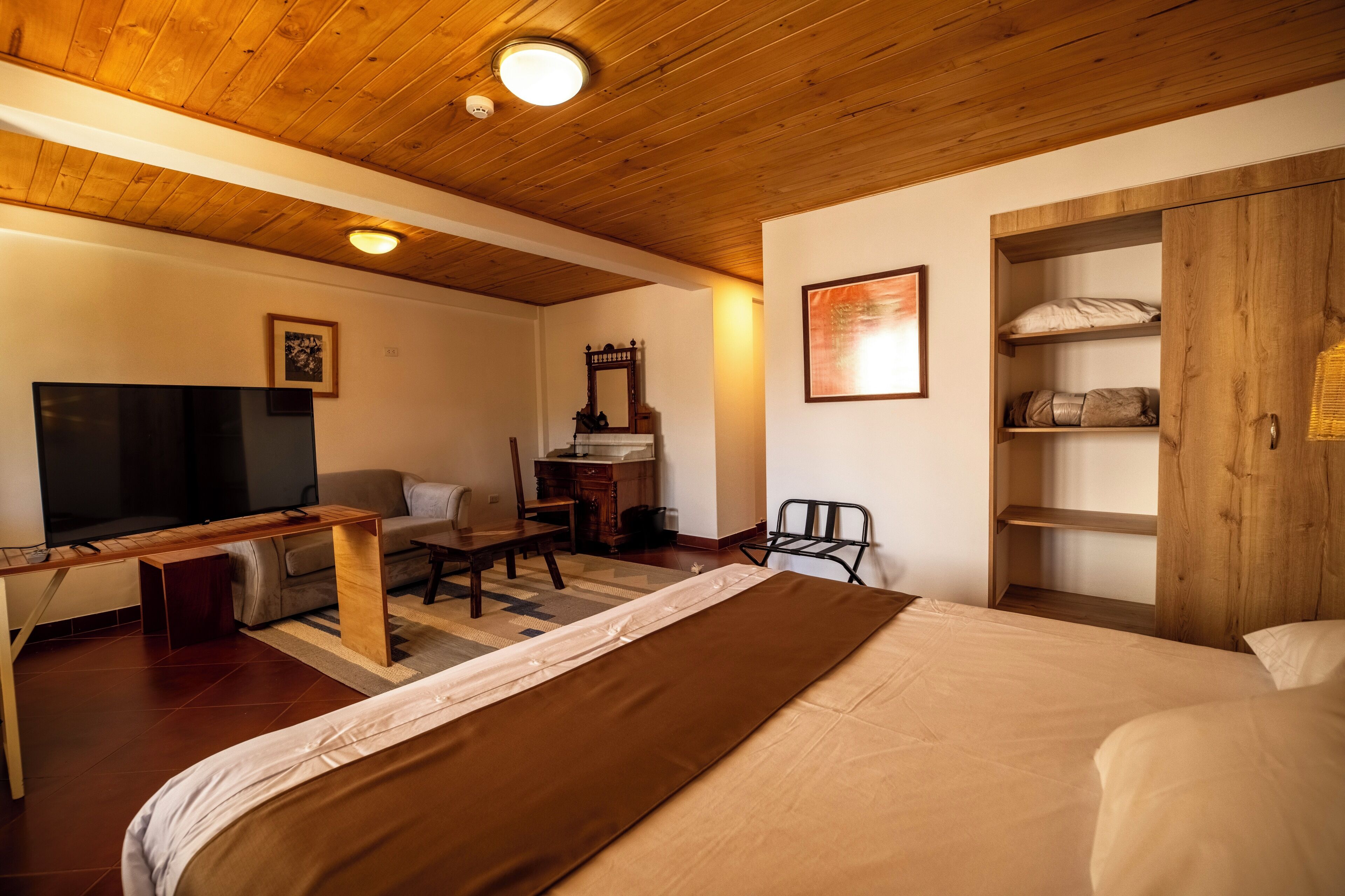 A room with a bed, a TV, a desk, a chair, and a wardrobe.
