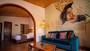 A room with a bed, a blue sofa, and a wooden coffee table. - San Sebastian Hotel Boutique (Huaraz)