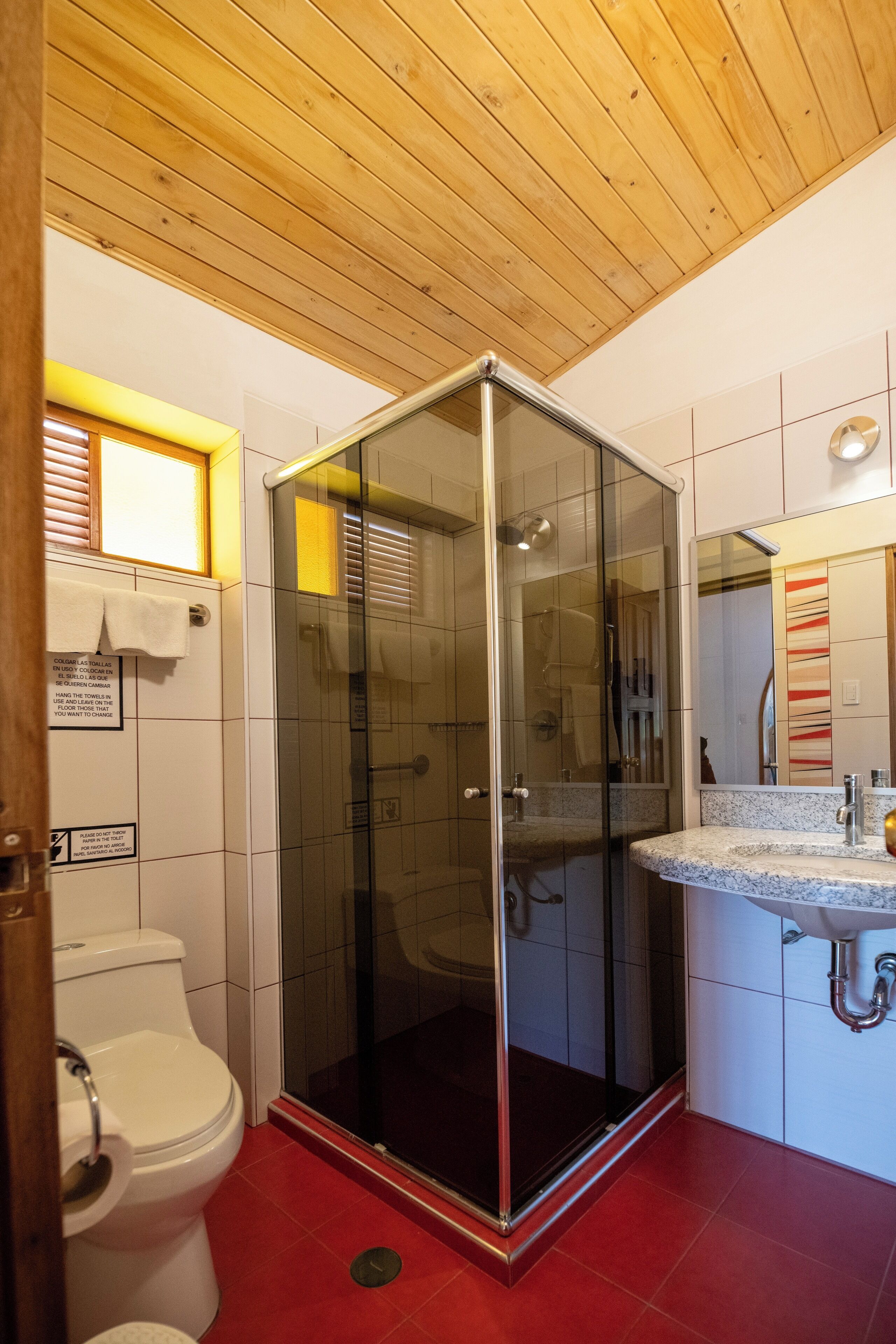 A modern bathroom with a glass-enclosed shower, a white toilet, and a sink with a marble countertop.