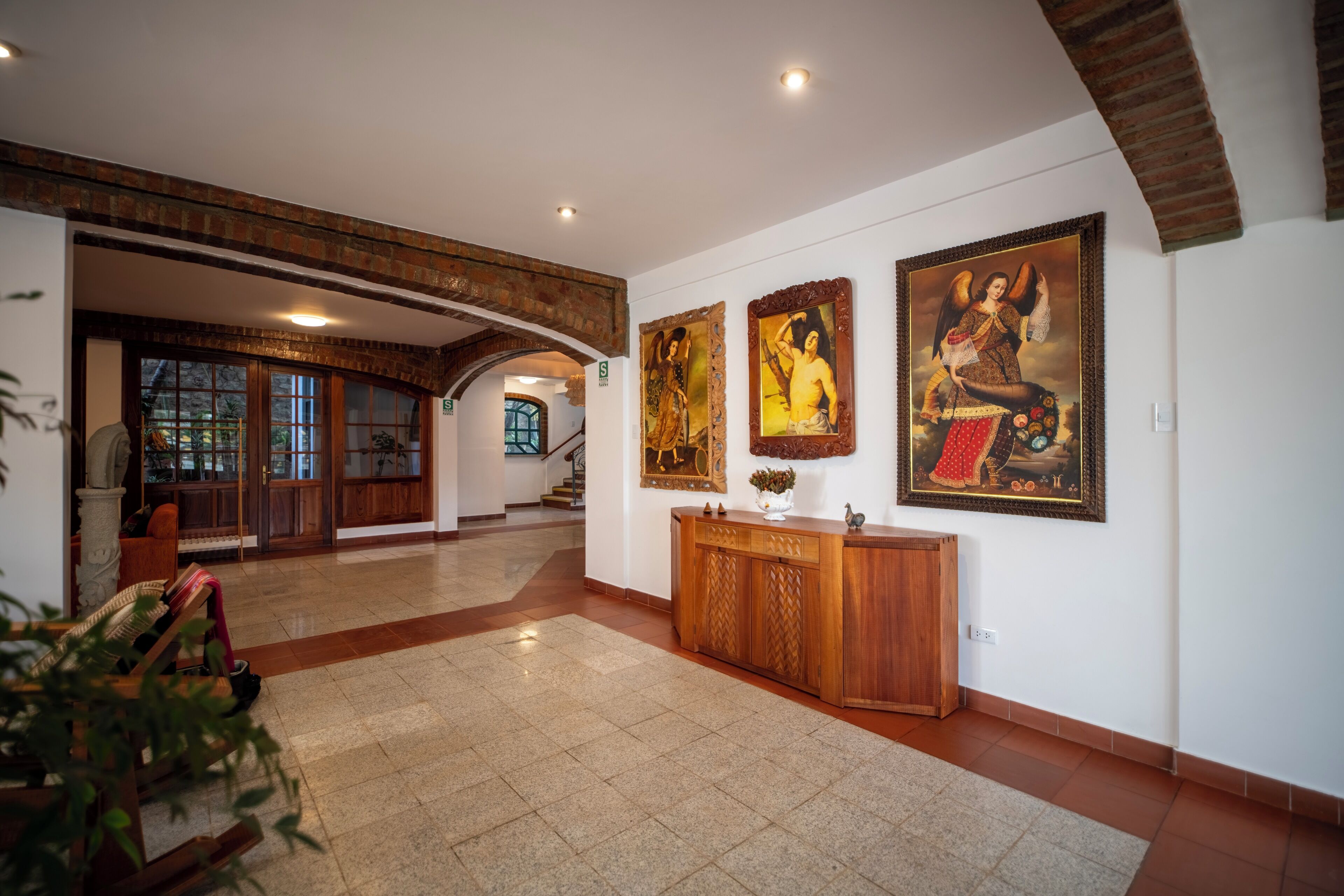 Un'ampia hall con una scrivania in legno per la reception, una scala e opere d'arte alle pareti.