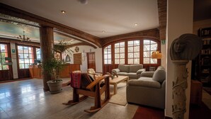 A spacious lobby with a large wooden rocking chair, a sofa, and a stone bust sculpture. - San Sebastian Hotel Boutique (Huaraz)