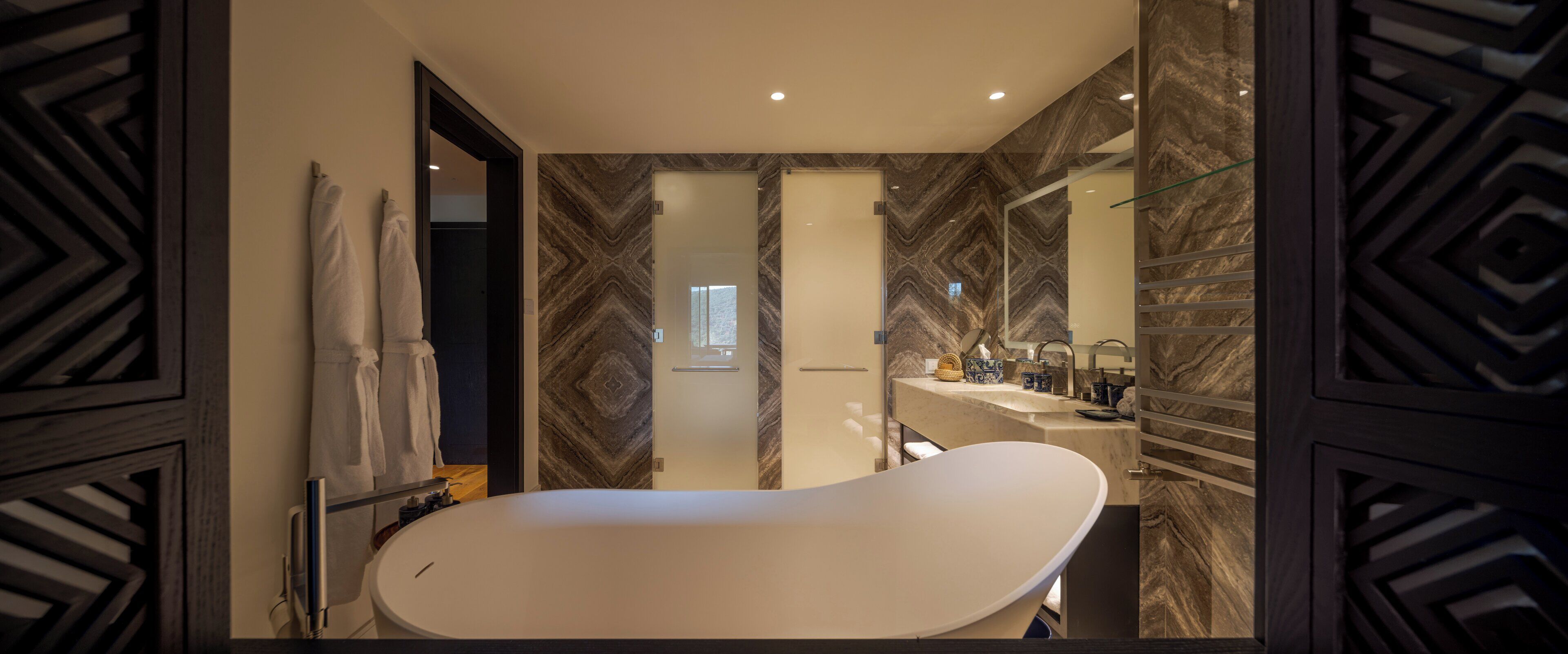 Une salle de bain moderne avec une baignoire sur pieds, un meuble-lavabo avec miroir et des murs en marbre.