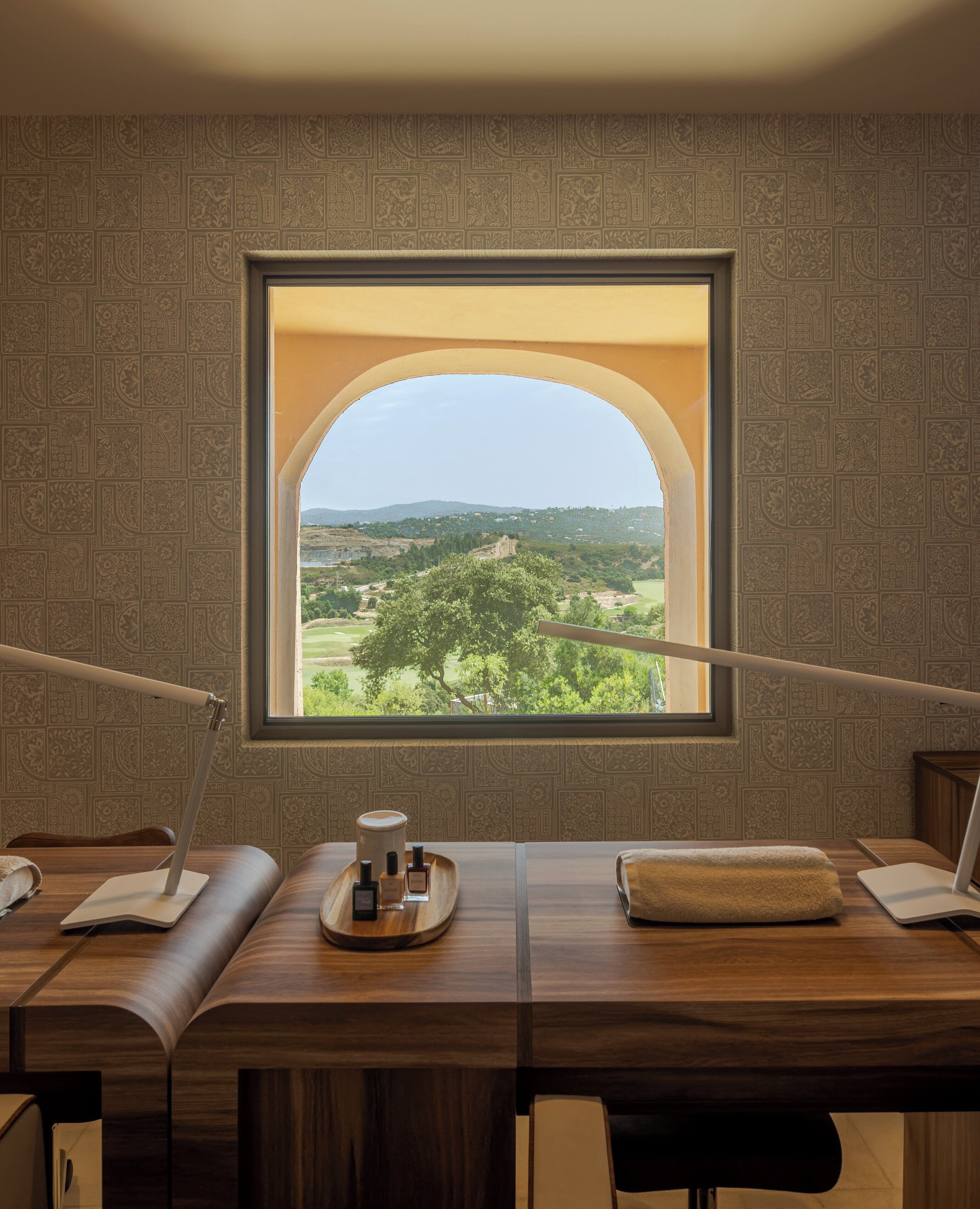 Una habitación con un amplio ventanal que ofrece vistas a un paisaje verde y colinas distantes.