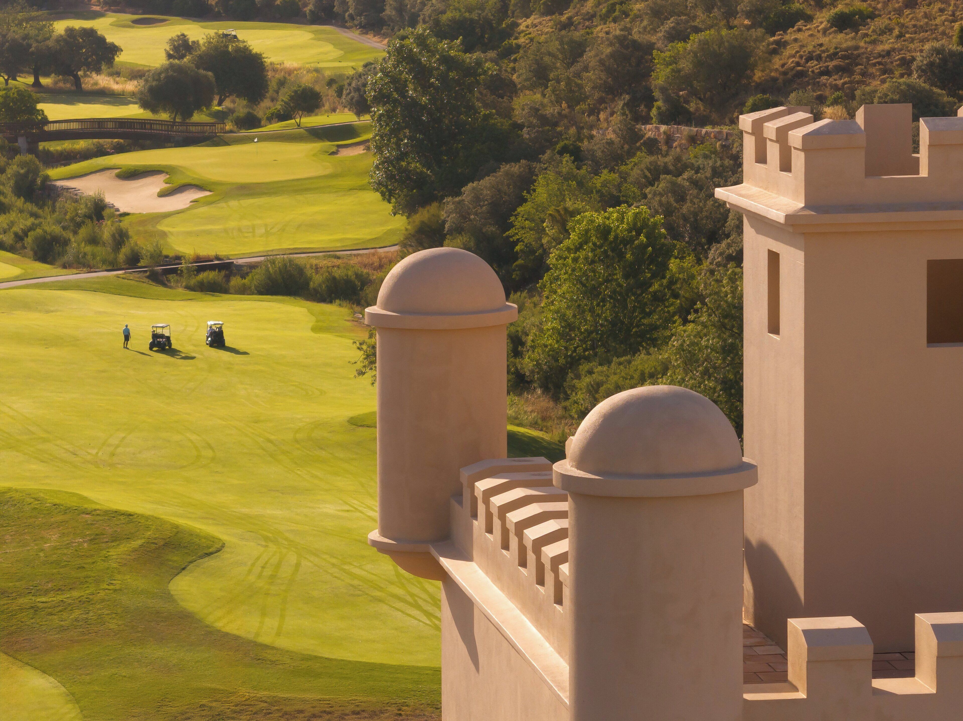 Un parcours de golf doté de bunkers, d’un pont et d’une structure ressemblant à un château, avec des tours.