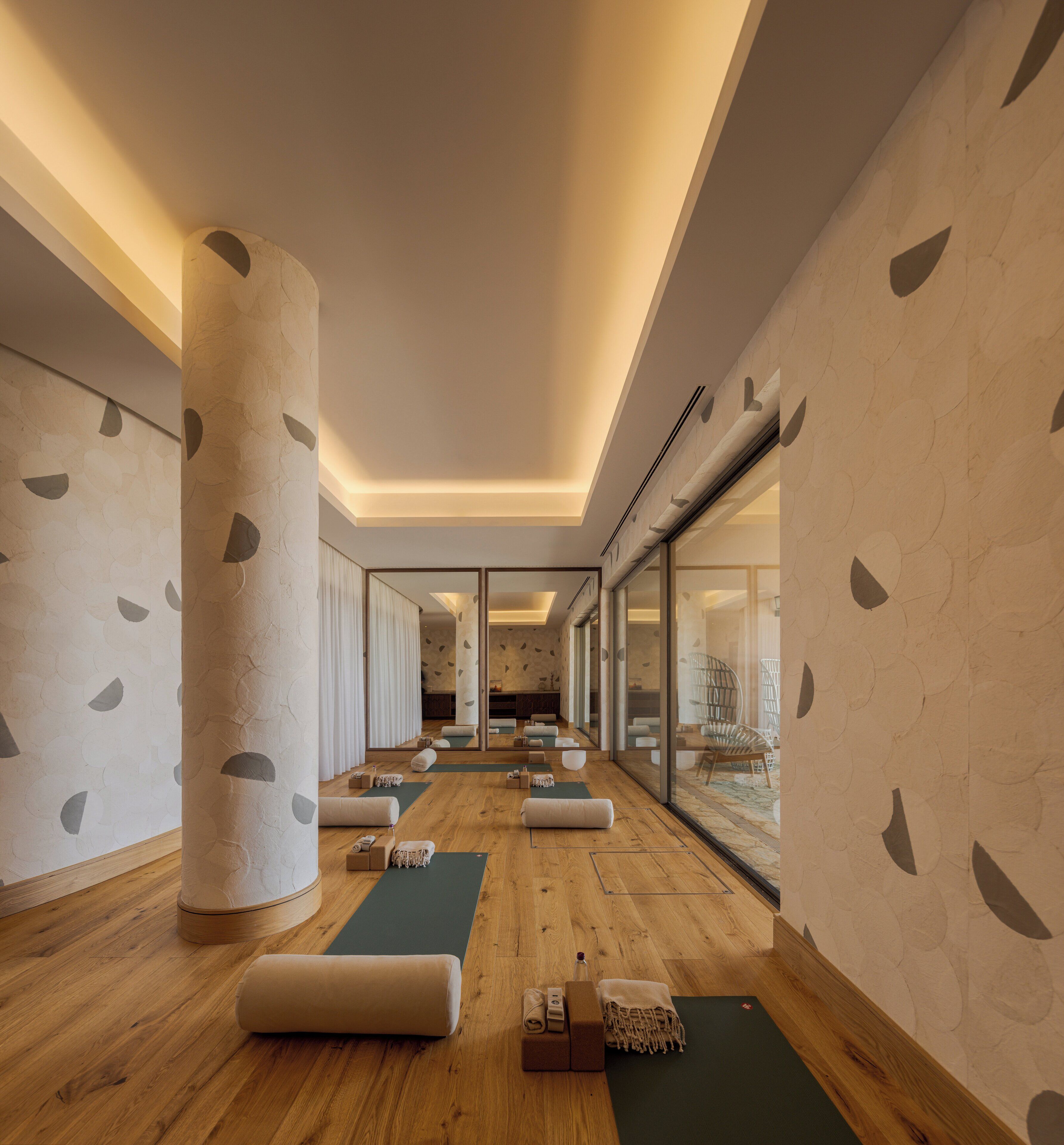 A modern spa room with wooden flooring, large columns, and a mirrored wall.