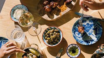 Una mesa de madera con varios platos, incluyendo aceitunas, almejas y carne, junto con varias copas de vino.