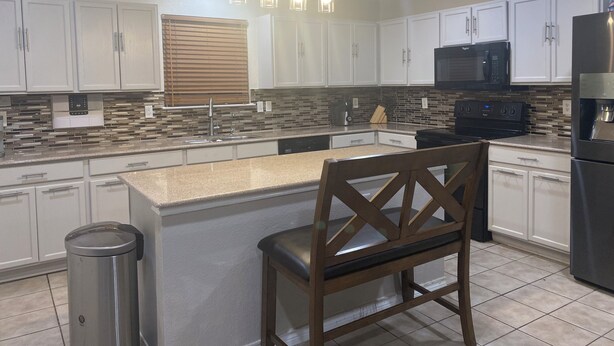 A modern kitchen with white cabinets, a black stove, a microwave, and a stainless steel refrigerator. - Charming 4-bedroom house with AC and WiFi in amazing Cedar Hill (Cedar Hill)