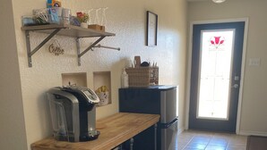 A kitchen with a wooden countertop, a coffee maker, a microwave, and a refrigerator. There is a shelf above the countertop holding various kitchen items. - Charming 4-bedroom house with AC and WiFi in amazing Cedar Hill (Cedar Hill)