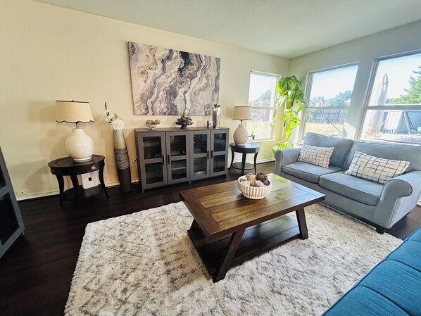 A living room with a grey sofa, a coffee table, a cabinet, and a painting on the wall.