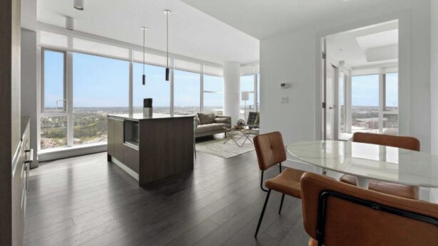 A spacious living area with a large glass table, a sofa, and a kitchen island. - Midnight Rose-Your Elevated Stay! (Calgary)