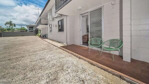 Un immeuble de deux étages doté d’un balcon, d’un patio couvert et d’une entrée sécurisée par un portail.
