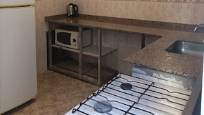 Eine Küche mit Gasherd, Mikrowelle, Kühlschrank und Spüle.