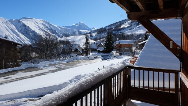 A snowy mountain village with wooden buildings and a clear view of snow-covered peaks.