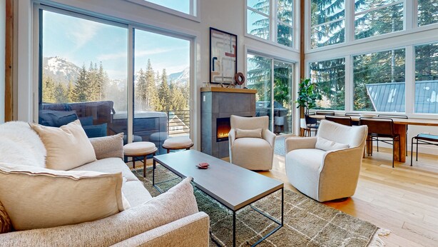 A spacious living room with a fireplace, large windows, and a view of mountains. - Luxury Lodge w/ Breathtaking Mountain Views, large yard, fireplace  & WIFI (Snoqualmie Pass)