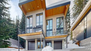 A modern two-story house with a wooden deck and large windows. - Luxury Lodge w/ Breathtaking Mountain Views, large yard, fireplace  & WIFI (Snoqualmie Pass)