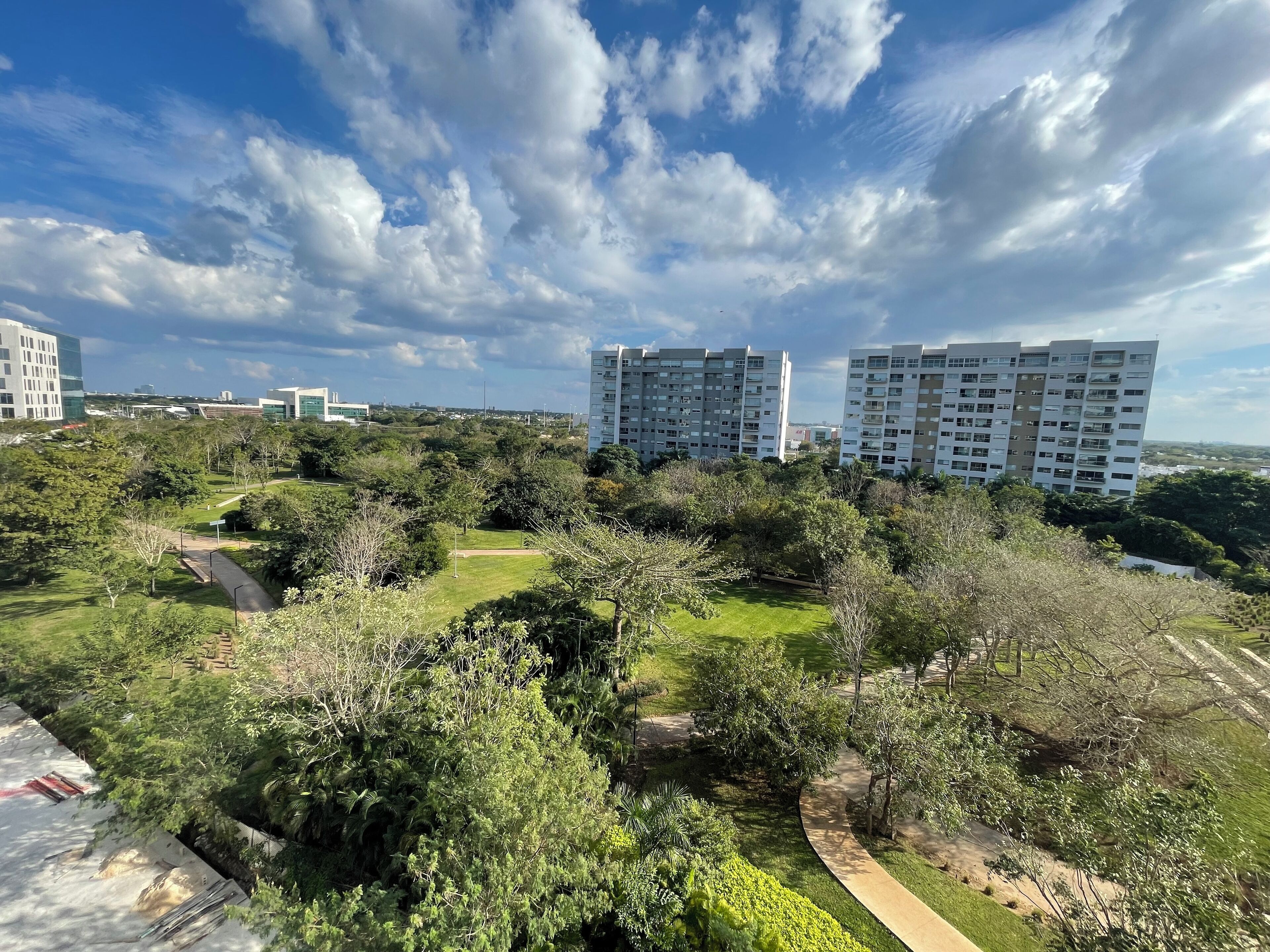 A residential area with modern apartment buildings, green spaces, and a clear sky.