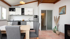 A modern kitchen with white cabinets, a dining area with grey chairs, and a fireplace. - Charming Villa Azul with Pool, Jacuzzi & Sauna (Sveti Vid Dobrinjski (Krk))