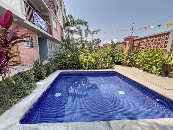 A rectangular swimming pool with blue tiles, surrounded by a concrete deck. - Warm Haven in Puerto Vallarta 2 Bedrooms (Puerto Vallarta)