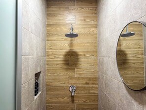 A bathroom with wooden panel walls, a round mirror, and a shower with a circular head. - Warm Haven in Puerto Vallarta 2 Bedrooms (Puerto Vallarta)