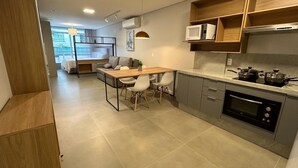 A modern kitchen with a dining area, built-in appliances, and a view of the living room. - Beautiful Studio 200m from Beira Mar, Center of Florianópolis! (Centro Florianópolis)