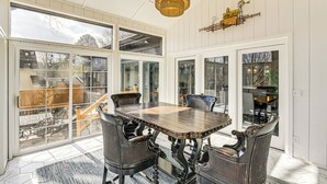 A sunroom with a large table and chairs, large windows, and a hanging light fixture. - Fish, Boat & Unwind: Old Hickory Lake Retreat (Mt. Juliet)