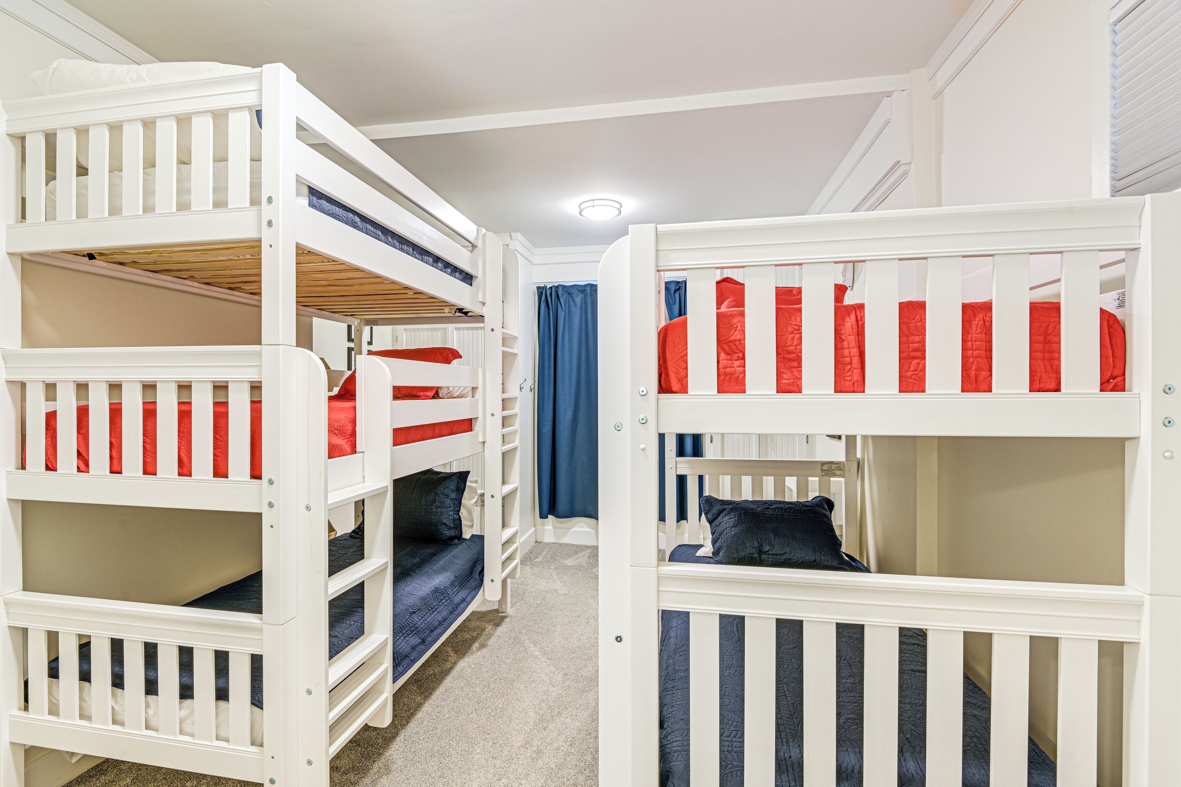 Une chambre avec un lit superposé, des barreaux blancs et une literie bleue.