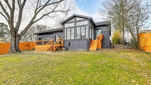 A modern house with a large window, a wooden deck, and a tree in the yard. - Fish, Boat & Unwind: Old Hickory Lake Retreat (Mt. Juliet)
