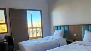 A hotel room with two beds, a desk, and a chair. - Hotel nakhil dak (Dakhla)