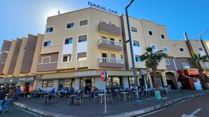 A hotel with multiple floors, outdoor seating, and a clear sky. - Hotel nakhil dak (Dakhla)