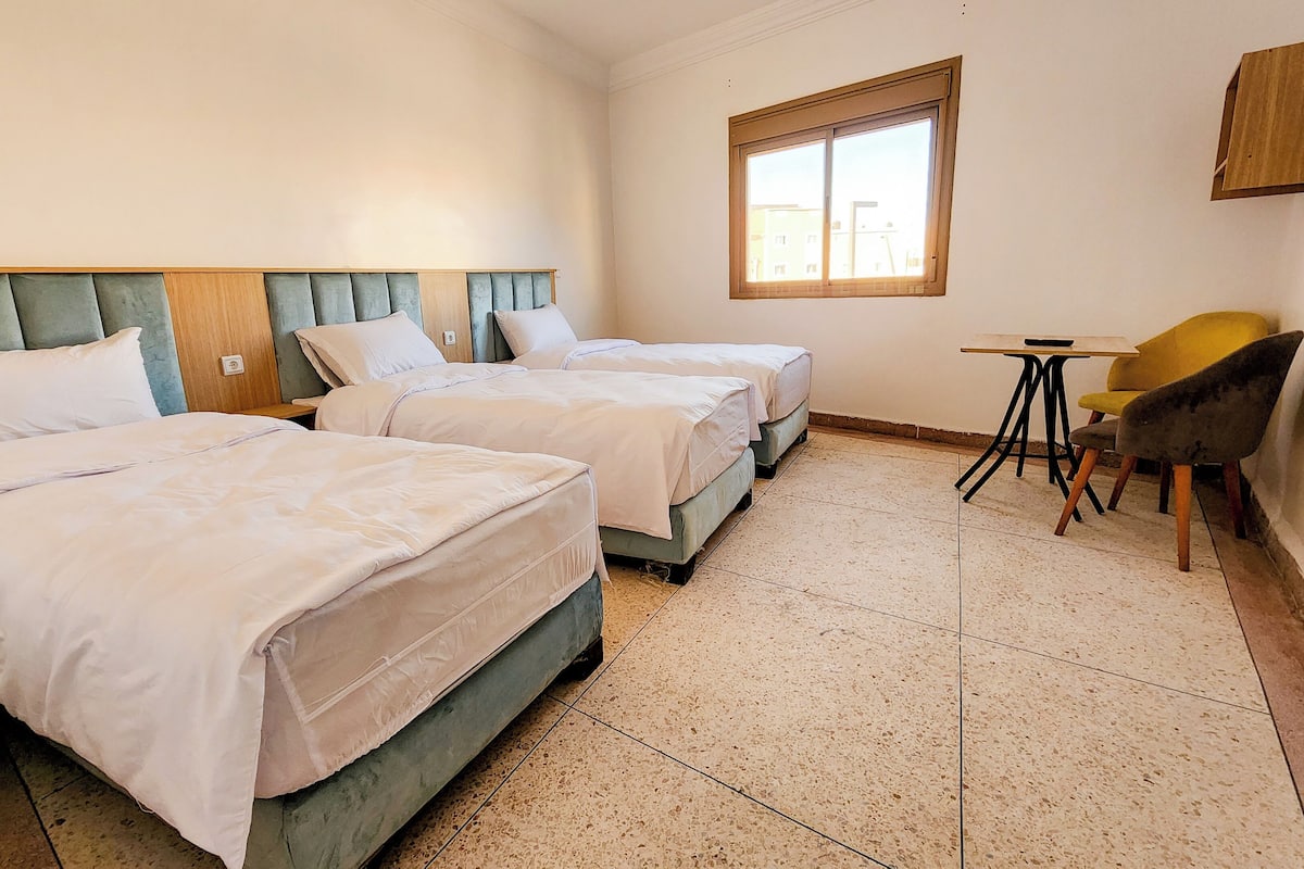Une chambre d’hôtel avec deux lits, une petite table et une chaise.