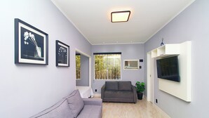 A modern living room with a grey sofa, a flat-screen TV mounted on the wall, and framed pictures on the wall. - Pompeu Loureiro (Rio de Janeiro)