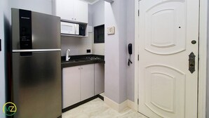 A compact kitchen with a stainless steel refrigerator, a microwave, and a sink. - Pompeu Loureiro (Rio de Janeiro)