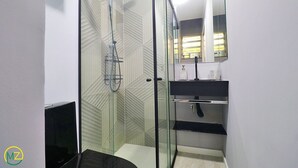 A modern bathroom with a glass shower enclosure, a black sink, and a mirror above the sink. - Pompeu Loureiro (Rio de Janeiro)
